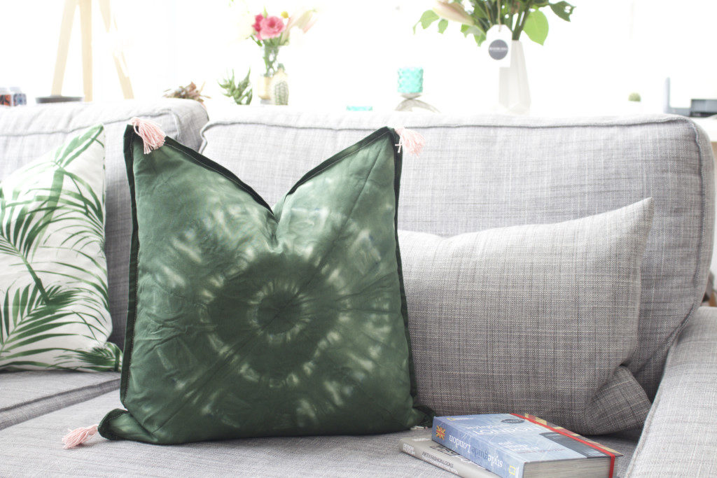 DIY Batik Kissen mit Quasten selber machen - grünes Batik Kissen auf grauem Sofa